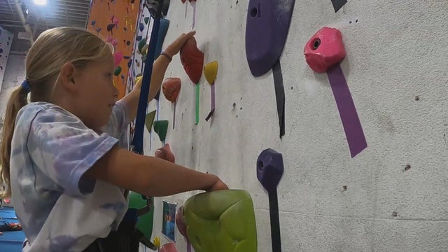 A young girl climbs a rock wall at Camp Rock 